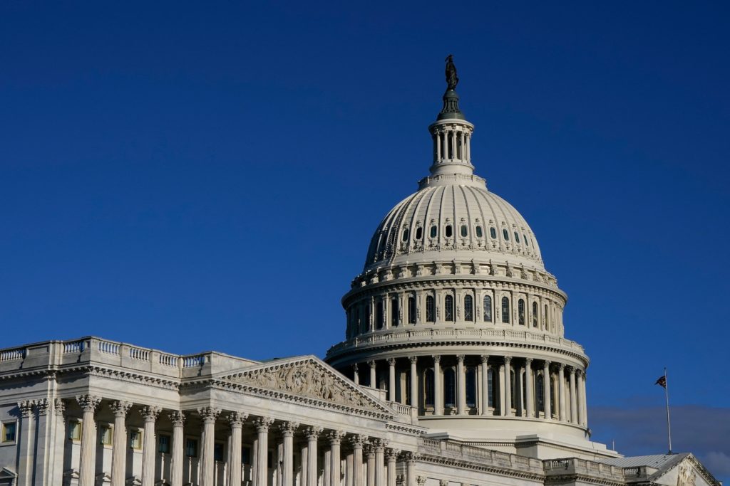 The U.S. Capitol dome and west front under a clear sky.
