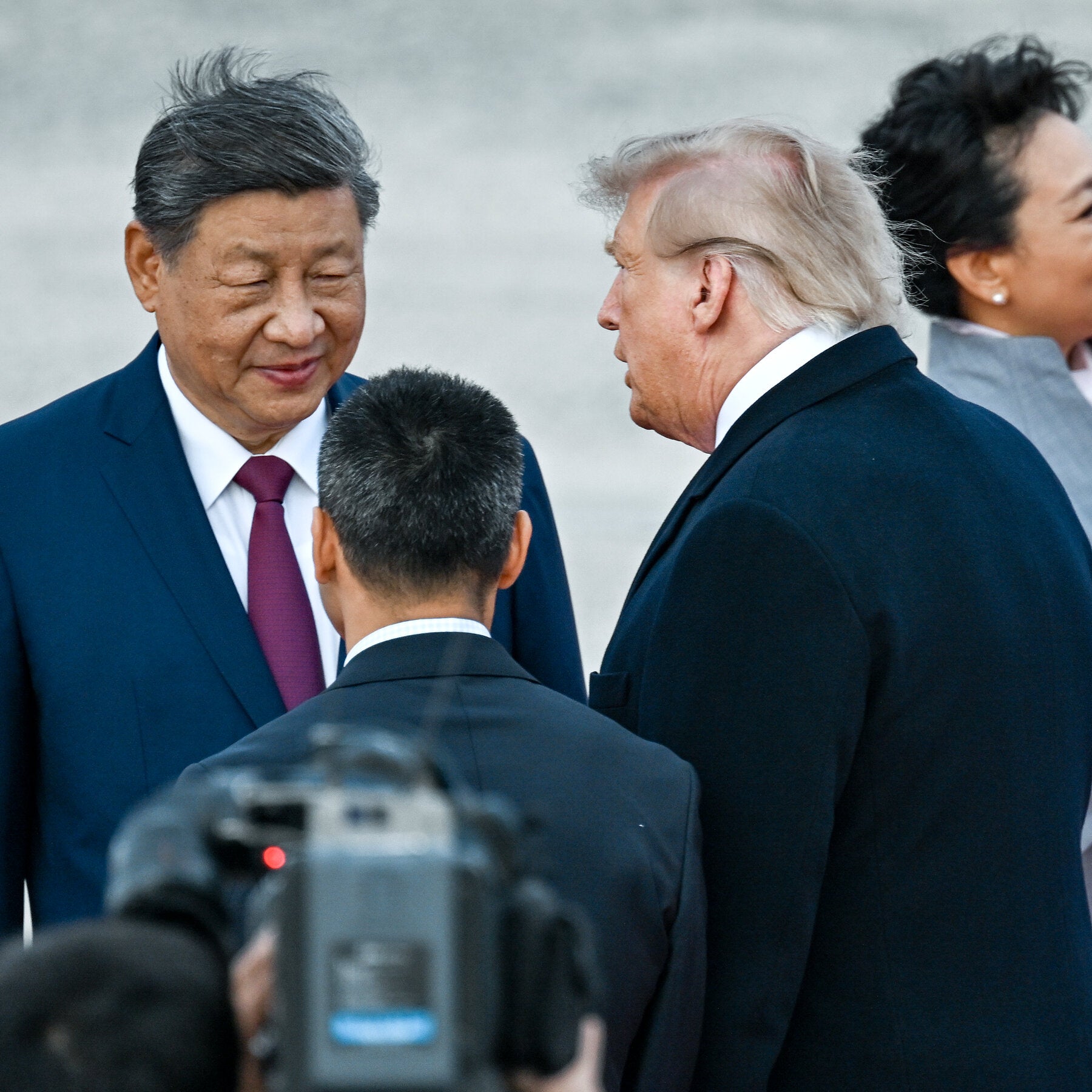 Xi and Trump speak face-to-face while aides, cameras, and other attendees crowd the foreground and background.