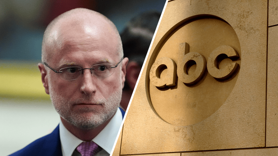 A bald man wearing glasses appears beside an ABC logo mounted on a stone wall.