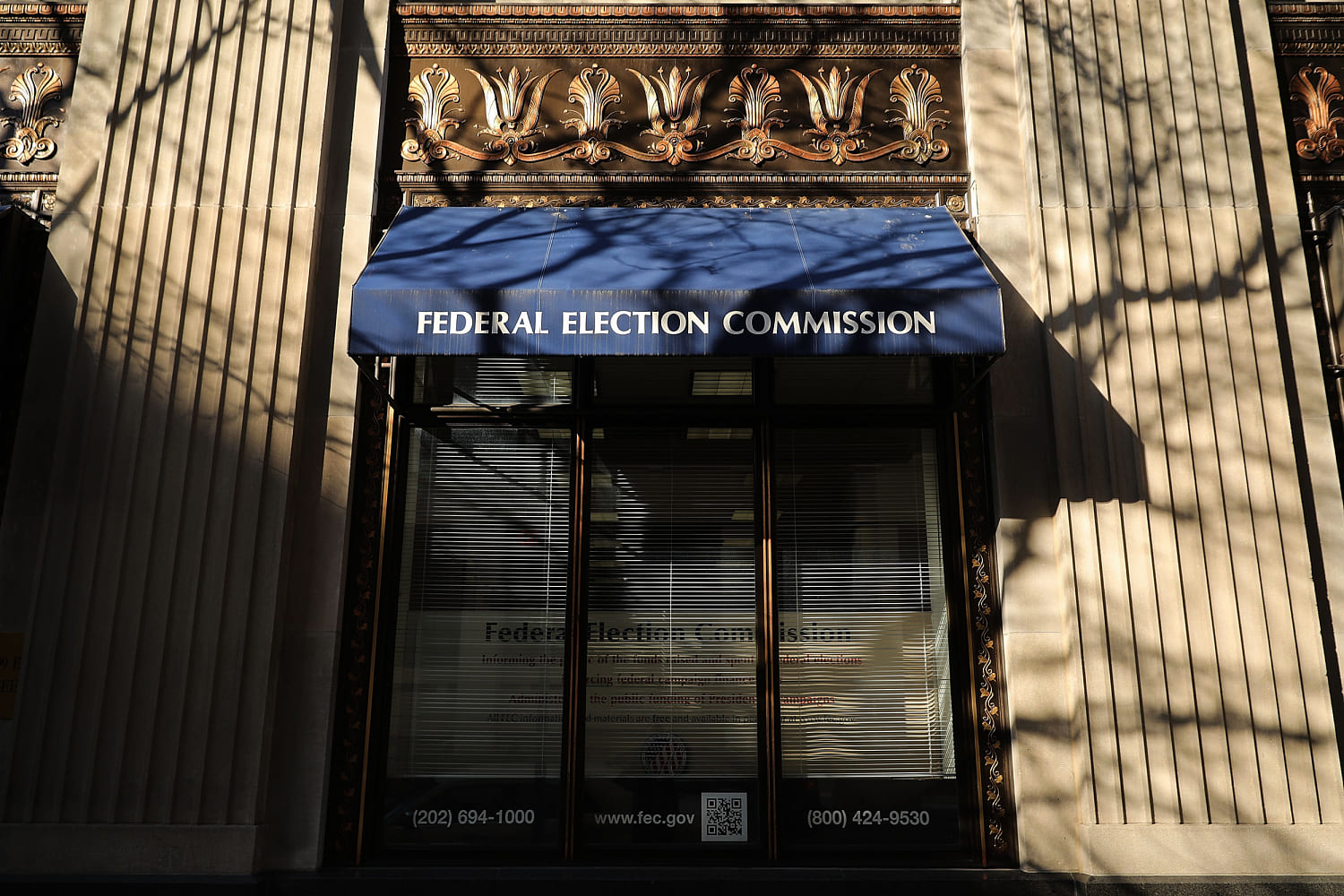 A blue awning reading “Federal Election Commission” hangs over a glass entrance, with tree shadows across the stone front.